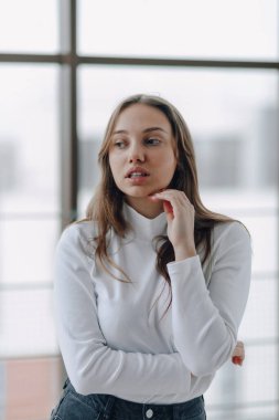 Pencerenin arkasındaki çekici genç kız farklı duygular ve ruh hali gösteriyor. Kapalı alanda hafif arka planda bir kız.
