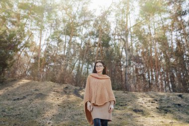 Orman arka planında güneşli bir günde telefonuyla doğada genç ve çekici bir kız. Açık hava tatilleri ve teknolojiye ve internete bağımlılık.