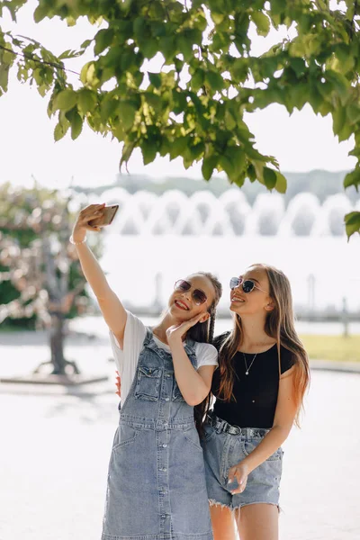Két Fiatal Csinos Lány Sétál Parkban Képeket Készítenek Magukról Telefonban — Stock Fotó