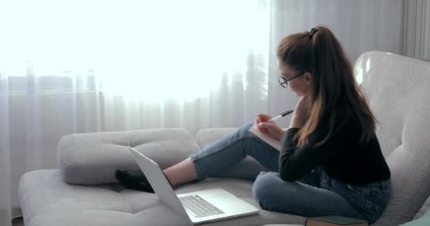 Chica trabajando en el ordenador portátil en casa en el sofá. Quédese en casa y trabaje remotamente. aislamiento en casa . — Vídeo de stock