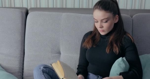 Hezká dívka čte knihu na gauči. Zůstaň doma a uvolni se. sebezdokonalování. kniha papíru. — Stock video
