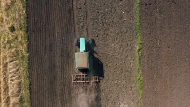 Ovanifrån, flygbild. traktorn odlar marken. Förberedelser för odling av grödor. jordbruk i byn och på landsbygden. — Stockvideo