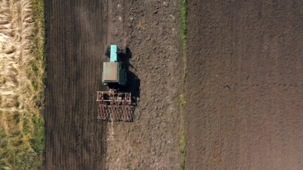 Draufsicht, Luftaufnahme. Der Traktor bewirtschaftet das Land. Vorbereitung auf den Anbau von Feldfrüchten. Landwirtschaft im Dorf und auf dem Land. — Stockvideo