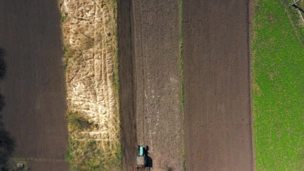 Privire de sus, vedere aeriană. Tractorul cultivă pământul. pregătirea pentru cultivarea culturilor. Agricultura în sat și în mediul rural . — Videoclip de stoc