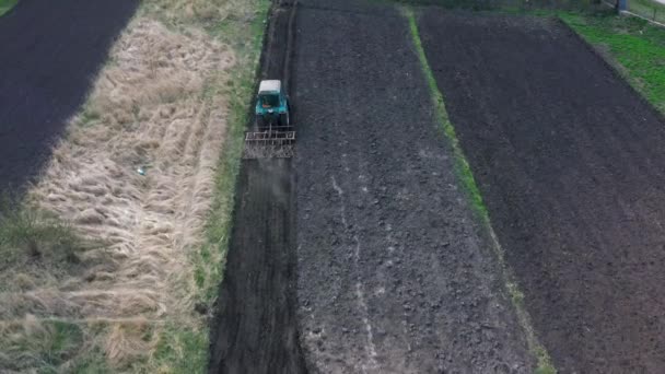 Bovenaanzicht, luchtaanzicht. de trekker verbouwt het land. voorbereiding op de teelt van gewassen. landbouw in het dorp en op het platteland. — Stockvideo