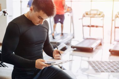 Genç antrenör spor salonunda notlar alıyor. Spor için özel antrenör. spor ve spor.