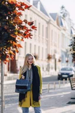 Güzel, mutlu, çekici, sarışın kadın. Sıcak ve güneşli bir havada sokakta paketleri var. alışveriş ve olumlu duygular.
