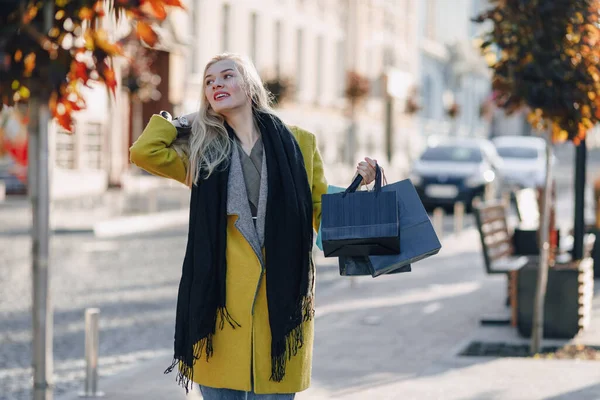 Güzel, mutlu, çekici, sarışın kadın. Sıcak ve güneşli bir havada sokakta paketleri var. alışveriş ve olumlu duygular.