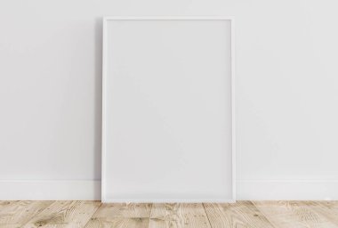 Empty thin white frame on light wooden floor with white wall behind it. Empty poster frame mockup. Empty picture frame mockup. Blank photo frame.