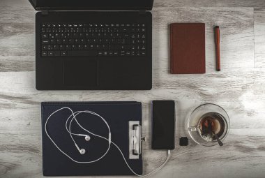 Bilgisayarlar, cep telefonları, not defterleri gibi beyaz ahşap bir masa üzerinde çalışan bir kişinin iş yardımcıları ve çayı.