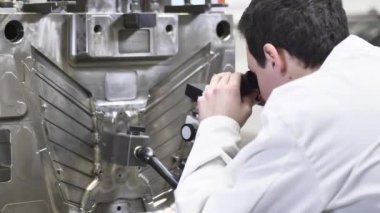 Enjeksiyon kalıbındaki eksiklikleri mikroskopla kontrol eden kalite mühendisi Enjeksiyon kalıbının otomotiv fabrikasındaki teknik durumunu kontrol ediyor.