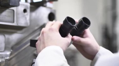 Enjeksiyon kalıbındaki eksiklikleri mikroskopla kontrol eden kalite mühendisi otomotiv fabrikasındaki enjeksiyon kalıbının teknik durumunu kontrol ediyor.