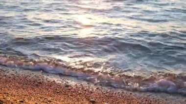 Deniz kıyısına yakın çekim için ideal bir manzara. Kumsal ve küçük çakıl taşları. Güneş suda parlıyor..