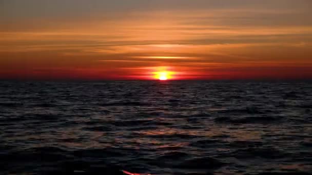 Timelapse de la puesta de sol de la noche. El sol está cayendo lentamente sobre el horizonte en el mar ondulado . — Vídeo de stock