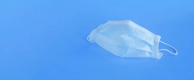 Mavi arka planda yüzü tıbbi maske şeklinde yatay bir pankart. Mesaj için yer var. Virüs koruma kavramı.