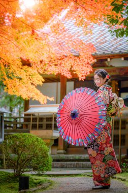Geleneksel ya da orijinal Japon kıyafetleri giyen eski moda bir kadın, köy bahçesinin ortasında tek başına yürüyor, Japon tarzı çekici.  