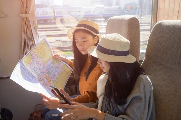 Women Traveller in transport on train looking in ordinary map and mobile GPS for properly destination, travel on public transport by owns way selection