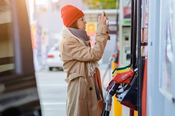 woman driver checking cost of gasoline, step flowing up and down of cost of gasoline in market makes worry to the cost of life of the people cosumption