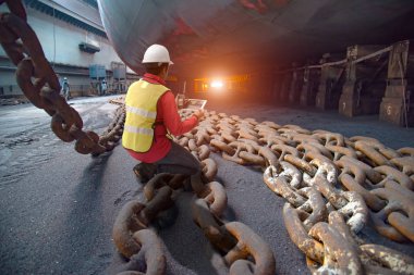 Stevedore, port controller, Port Master, surveyor inspect under bottom hull chains bundle of commercial ship in floating dry dock yard, recondition of overhaul repairing and repainting, working in dry dock yard