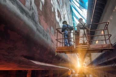 Steel basket carry by cherry picker crane for gang of worker power man, painting man or brush man working in high position, working at risk in dust under mesh sheet protection