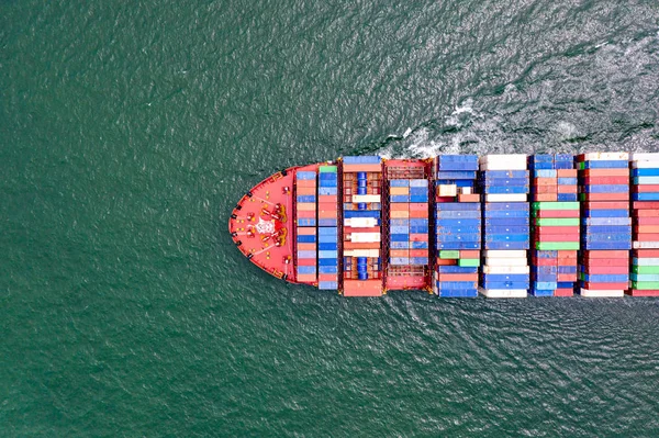 top aerial view of the large volume of TEU containers on ship sailing in the sea carriage the shipment from loading port to destination discharging port, transport and logistics services to worldwide