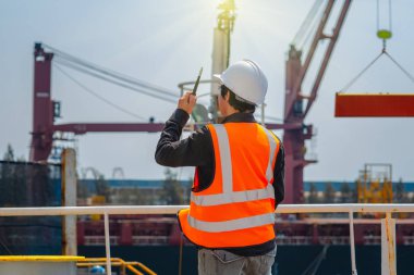 Liman işçisi, ustabaşı ya da mühendis, vinç sürücüsüne telsizle bağlanıyor. Malları ya da nakliyatı yüklerken güvenliği sağlamak için vinçle kaldırıyor.