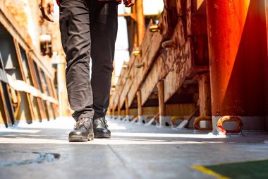 Mühendislik ya da teknisyen bacakları, güvenlik ayakkabısı giyen işçiler iş yerindeki çelik güvertede yürüyorlar.