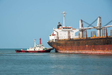 tug boat under pushing the ship to alongside the seaport terminal, docking yard, safety berthing the ship under navigating control by pilot and harbor master