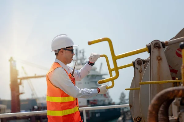 Hand of ship crew working on mooring winch of the commercial ship on berthing or un-berthing for safe sea fastening tight, Alongside the ship to the terminal works by mooring winch