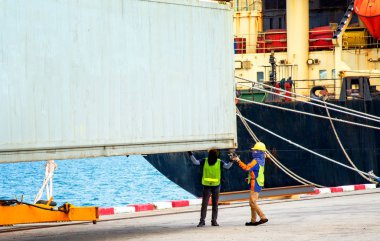 stevedore labor working on fitting refer container shoe to locking cone ready to loading and accomodate on the bay of the ship