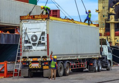 container unit being lift loading by the ship crane from the trailer to accommodation on bay storage, stevedore labor works in charge, the services of logistics and transport shipment to worldwide 