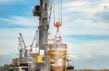 gantry crane of the port working with grab loading and discharging on hopper, bulk cargo ship carry on shipment works busy in port terminal