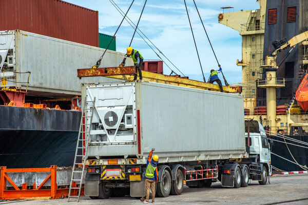 container unit being lift loading by the ship crane from the trailer to accommodation on bay storage, stevedore labor works in charge, the services of logistics and transport shipment to worldwide 