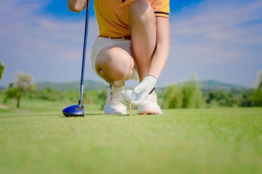 Hand of woman golfer laying golf ball ontoo wooden tee on tee off pin on the golf course, ready to hit ball away to the fairway