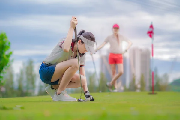 年轻女子高尔夫球手把球放在绿色的身体上推杆向目标得分 集中注意力学习投篮得分 — 图库照片