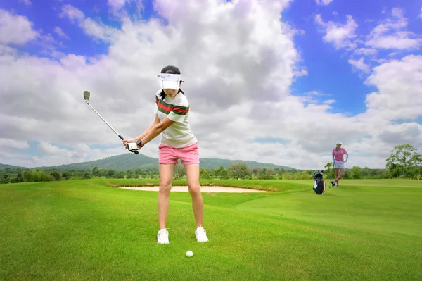 女子ゴルフ選手はフェアウェイから目的地のグリーンフェアウェイまでゴルフボールを打つためにセットアップされています — ストック写真
