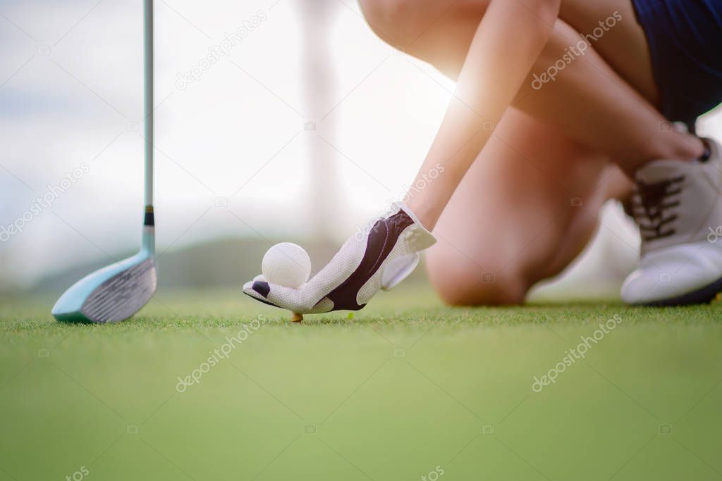 hand of young woman golf player holding golf ball push on wooden tee, ready to hit the ball to the destination target