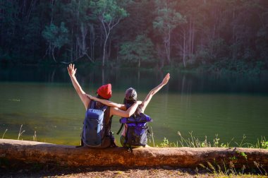 Kereste üzerinde oturan çiftler, orman ormanlarında seyahat romantizm vesilesiyle vahşi doğa seyahati