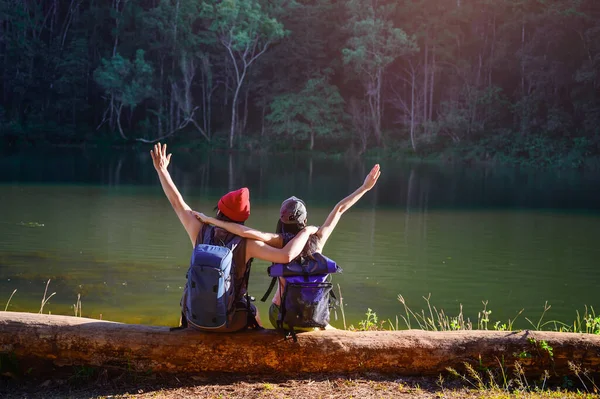 Kereste üzerinde oturan çiftler, orman ormanlarında seyahat romantizm vesilesiyle vahşi doğa seyahati