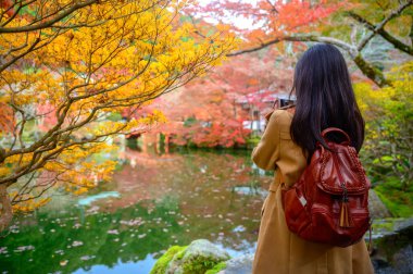 Gezgin kadın turistler Japonya 'nın sonbahar köyünün manzarasının keyfini çıkarıyor, Japonya' yı ziyaret eden turistler için popüler ve ünlü bir yerde sonbahar mevsimi değişimi yaşanıyor. 