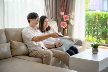 Karım ve kocam evde televizyon izlemekten zevk alıyor ve neşeyle eğleniyorlar.