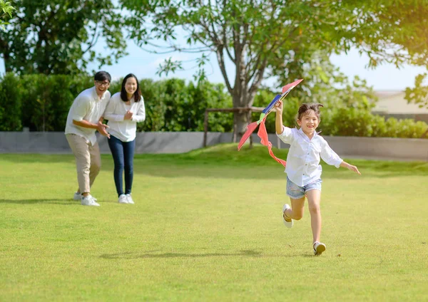 少女の娘が村の野外公園で凧を手にしてOファミリーを走らせ — ストック写真