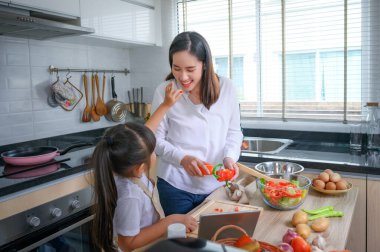 Anne ve kızı tatil evinde birlikte yemek pişirmenin keyfini çıkarıyorlar.