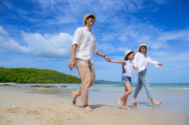 Anne ve baba, çocuğun elini tutmaya yardım eder, ilgi gösterir ve her zaman başarının hedefine destek olur. Deniz sahilinde el ele tutuşmanın tadını çıkarırlar.