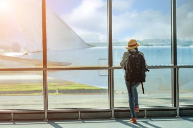 Havaalanının ulaşım alanında pasaportu olan kadın yolcu, bir sonraki seyahat programı için beklemede kalın, varış saatini geciktirin, uçuş kartını kontrol edin.