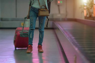 Kadın bagajı havaalanı terminalinin transfer kemerinden çeker ya da çeker, kadın yolcu varış salonundan uzaklaşır, varış konseptine doğru yol alır.