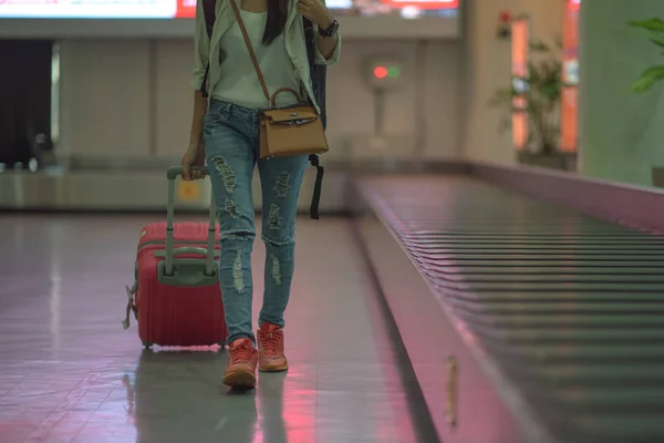 woman pull or towage drag of luggage away from transfer belt of the airport terminal, woman traveller to walks away from arrival hall, traveling to destination concept