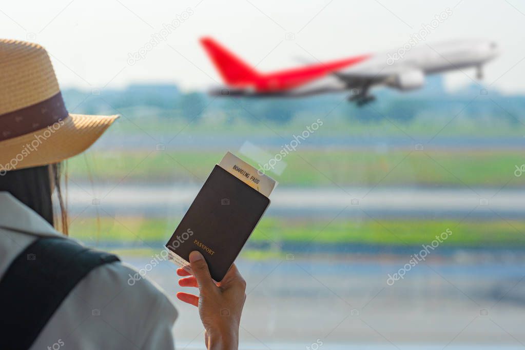 Hand of woman traveller holding passport waiting in transit area of airport, stand by for the next schedule traveling, late delay of the arrival departure, missing checking in the boarding pass