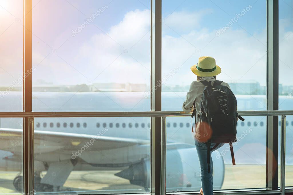 woman passenger traveler or tourist looking at the aircraft just leaving from the terminal, holding boarding pass in late checking in the gate entrance, upset and disaster disappointment traveling