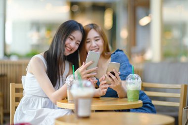 Her yerde sosyal medyayla çevrimiçi genç Asyalı kadınların her iki elindeki cihaz, dünya güncelleme medyasına bağlı canlı online yaşam.